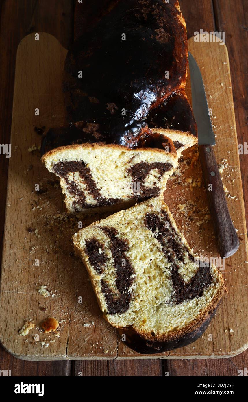 Cozonac, dolce tradizionale rumeno di Pasqua o di Natale. Tagliare il pane dolce su un tagliere di legno. Vacanze gastronomiche dell'Europa orientale. Foto Stock