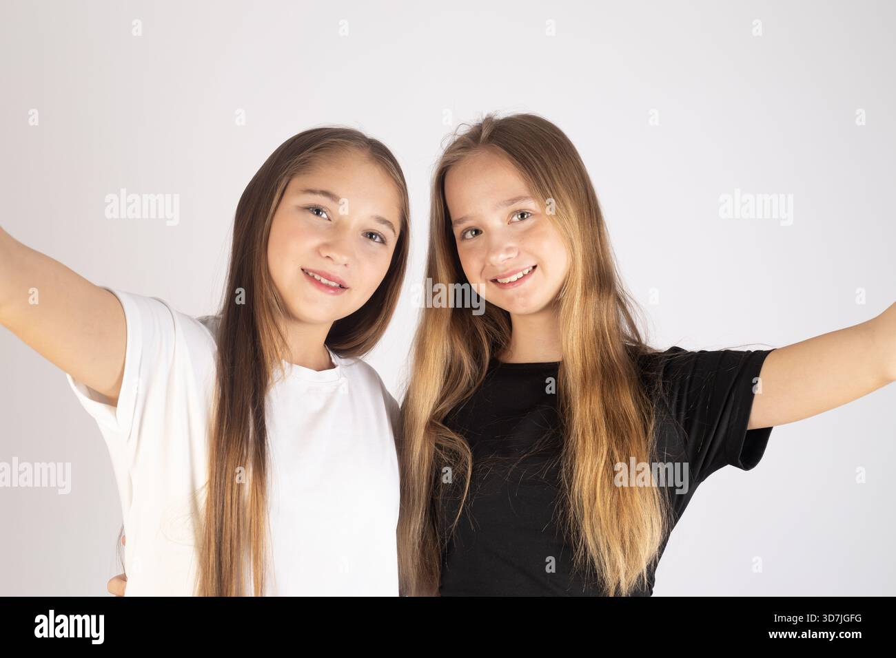 le ragazze nell'immagine sorridono alla telecamera con le braccia estese verso l'esterno. Foto Stock