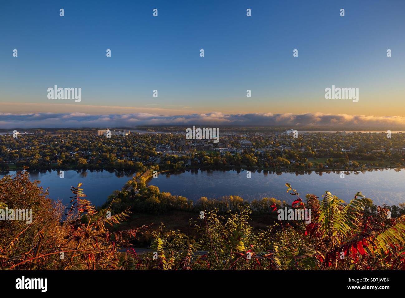 Una vista panoramica di una città lungo il fiume Mississippi con un lago in primo piano e nuvole di nebbia all'orizzonte. Foto Stock