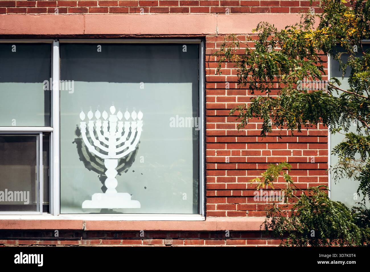 Montreal, Canada - 12 agosto 2025: Simbolo di Menorah in Jewish Quarter Mile End, vetrina sull'edificio in mattoni rossi Foto Stock