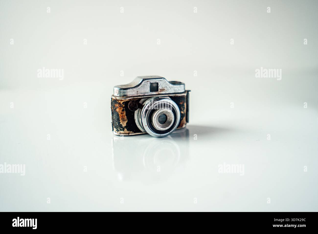 Piccola fotocamera in difficoltà che riflette la fotografia classica su uno sfondo chiaro Foto Stock