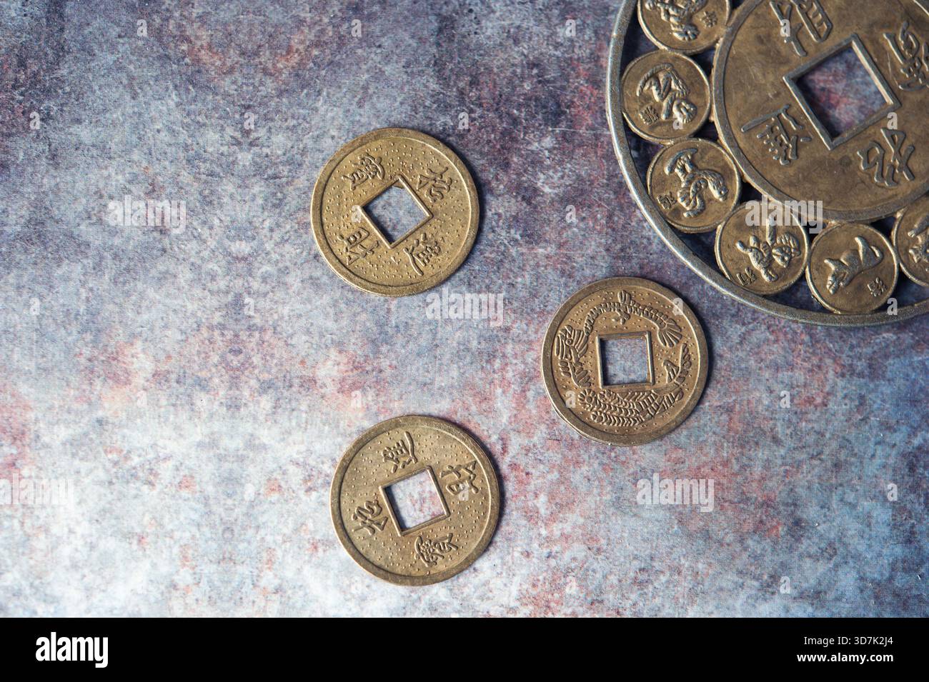 Tradizionali monete cinesi a foro quadrato disposte su fondo in pietra Foto Stock