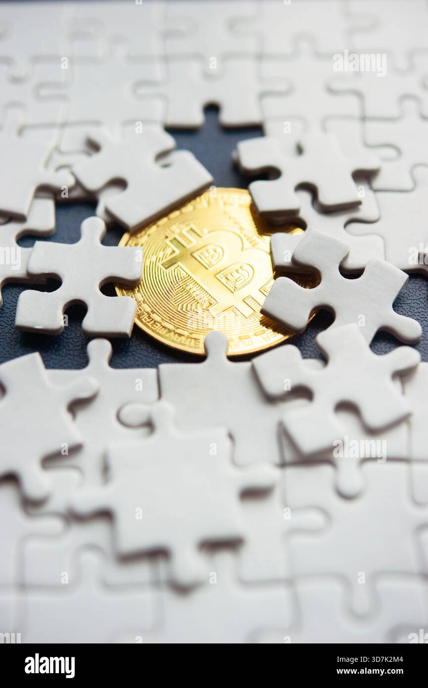 Moneta Bitcoin parzialmente rivelata sotto pezzi di puzzle bianchi che rappresentano il valore cripto nascosto Foto Stock