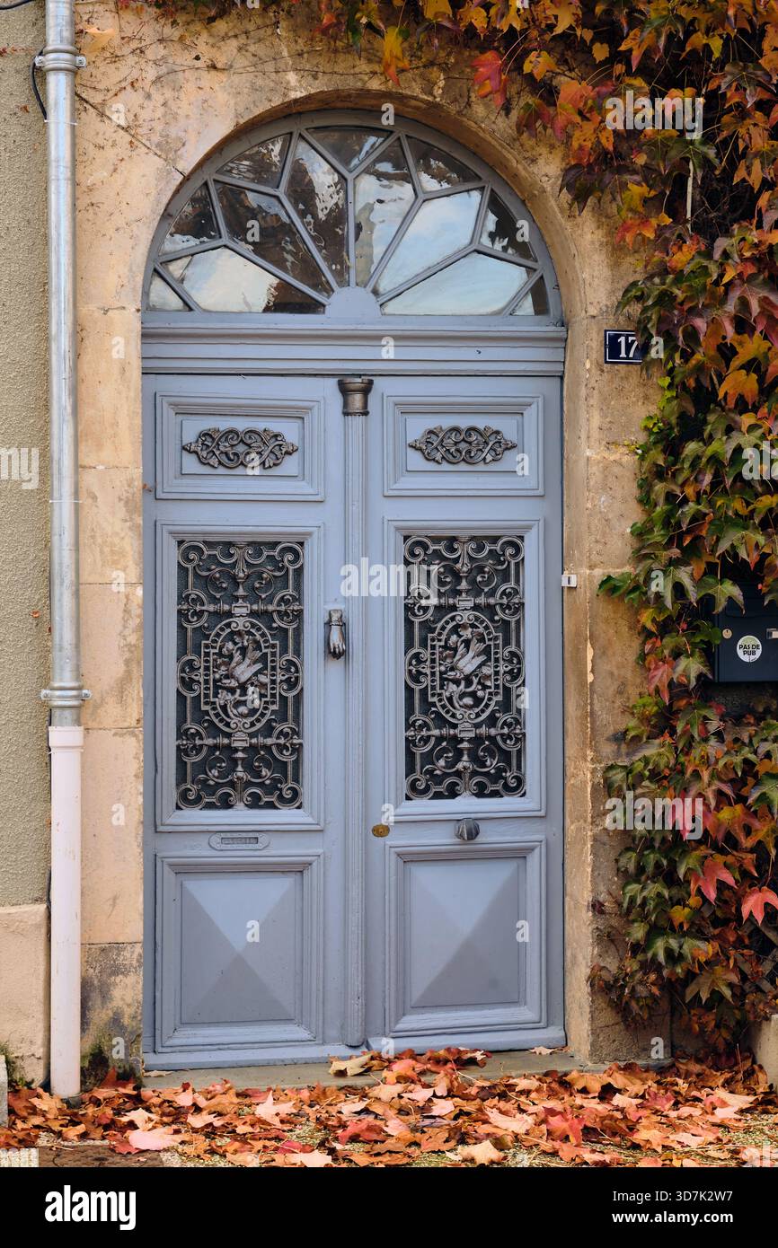 Boulonge-sur-Gesse, Francia; 12 novembre 2025: Porta storica del villaggio francese con lavori in metallo ornati e foglie autunnali che creano un'atmosfera storica Foto Stock