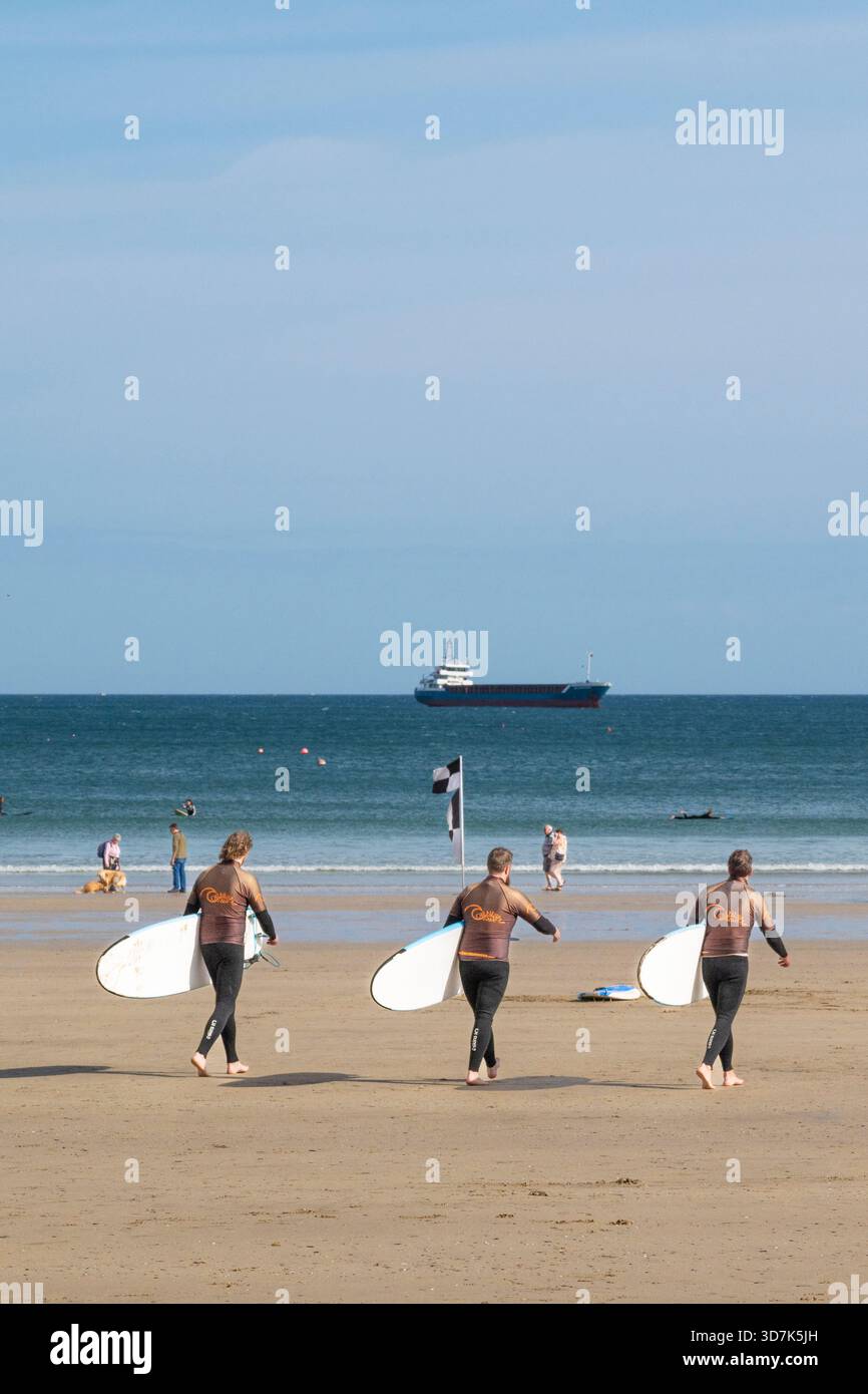 Tre vacanzieri in una lezione di surf con la Cornish Wave Surf School presso Towan Beach a Newquay, in Cornovaglia, in Inghilterra, nel Regno Unito. Foto Stock