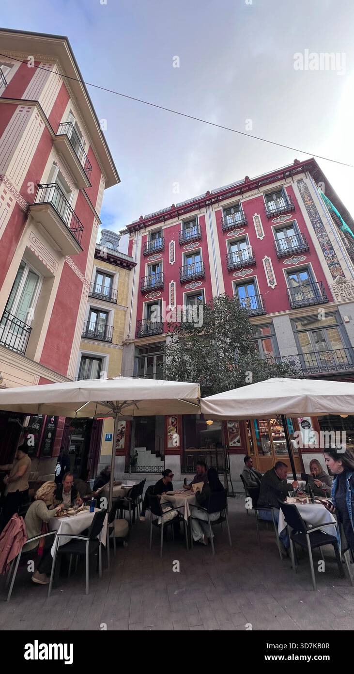 Un accogliente cortile di Madrid dove tavoli da terrazza, chiacchiere calde e facciate colorate trasformano un pomeriggio ordinario in un momento da cartolina. Foto Stock