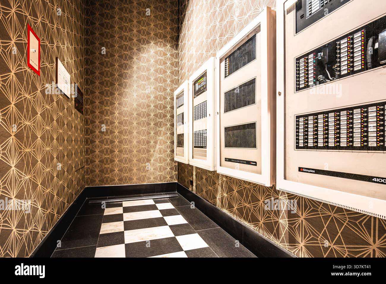 Sala di controllo elettrica con carta da parati a motivi geometrici e pavimento piastrellato in bianco e nero. Foto Stock