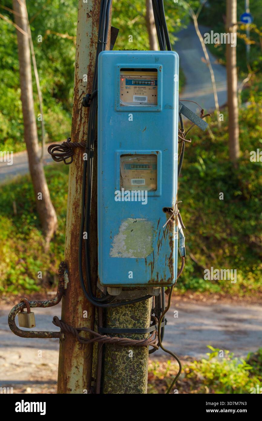 Vecchia scatola contatore elettrico su palo arrugginito Foto Stock