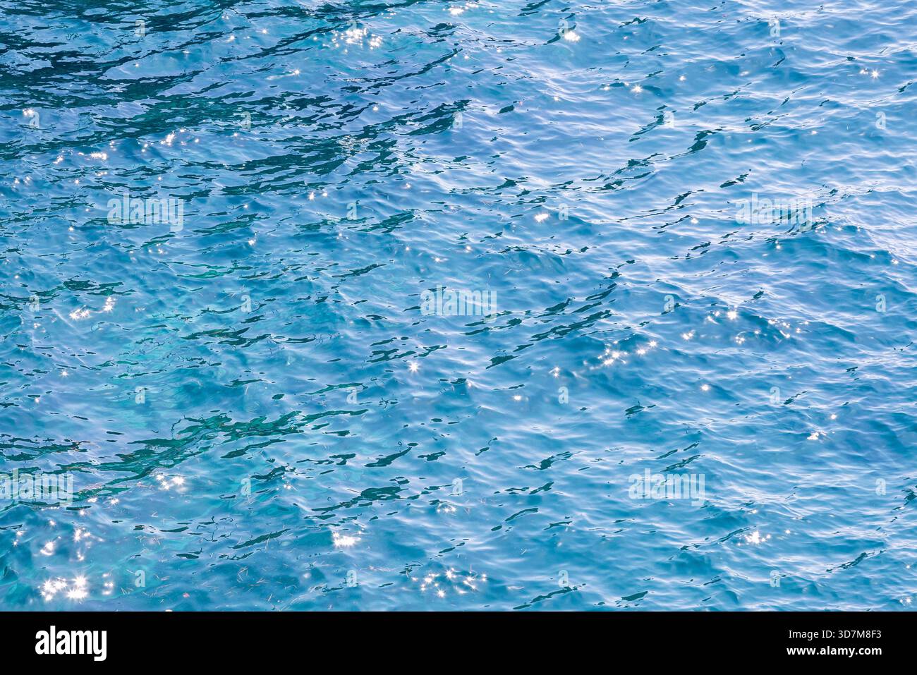 Superficie blu vivace dell'acqua marina con onde scintillanti e illuminate dal sole. Sfondo ideale per viaggi, natura e scene di sfondo. Testo foto di sfondo naturale Foto Stock
