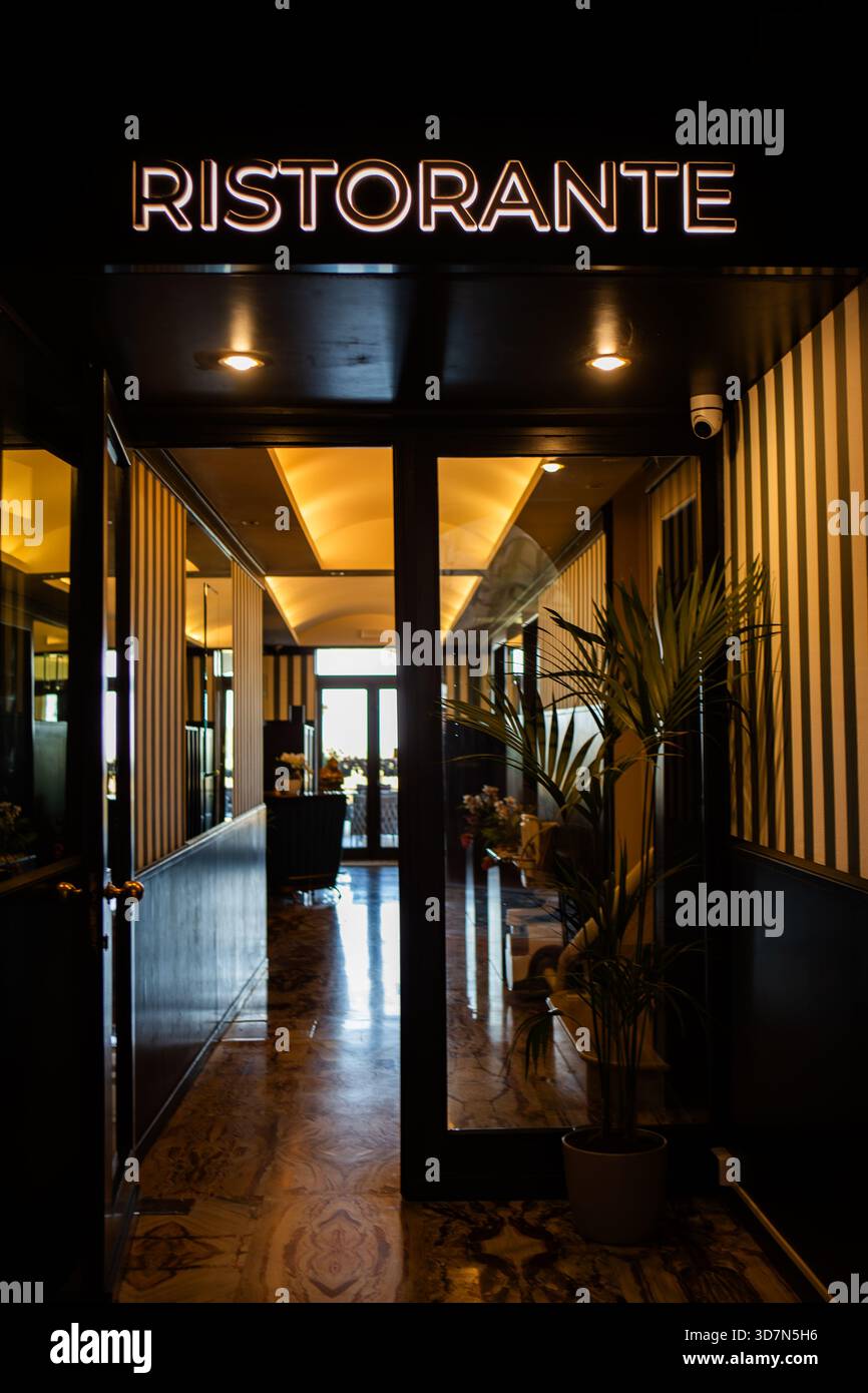 L'entrata di un raffinato ristorante italiano si illumina di luce calda rivelando un elegante pavimento in marmo dal design e eleganti dettagli a strisce sulle pareti. Foto Stock