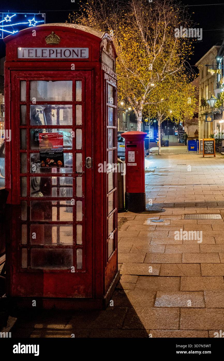 Iconica scatola telefonica rossa britannica e casella postale di notte - tradizionale scena di strada del Regno Unito con vibrazioni natalizie Foto Stock
