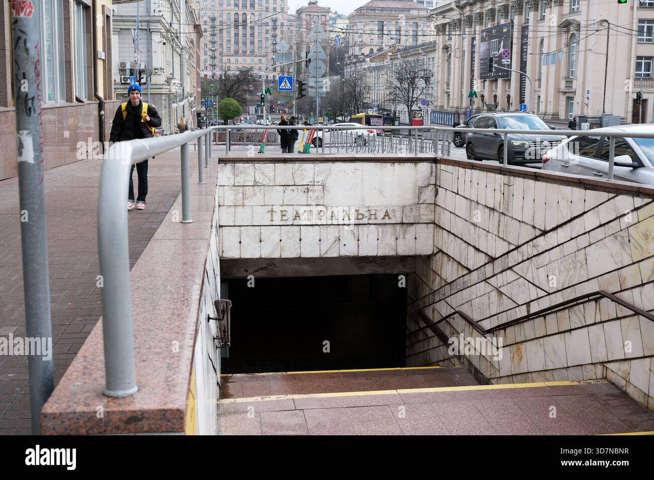 Le persone camminano accanto all'ingresso del teatro, ammirando le strade della città sopra. Kiev, Ucraina, 26 novembre 2025. Foto Stock