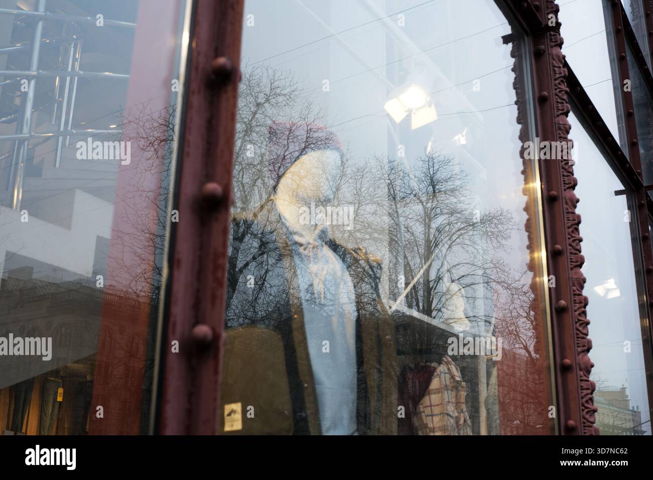Una vetrina di negozi in città mostra un outfit elegante accanto ai riflessi degli alberi. Khreshchatyk, Kiev, Ucraina. 26 novembre 2025. Foto Stock