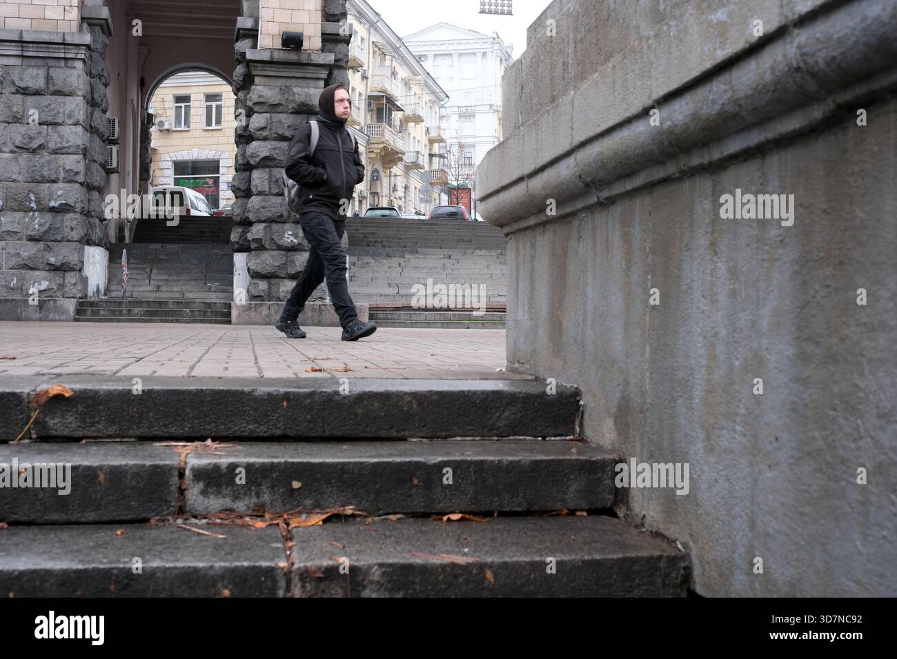 Una persona passeggia giù per scalini di pietra in una città, circondata da edifici tranquilli. Khreshchatyk, Kiev, Ucraina. 26 novembre 2025. Foto Stock