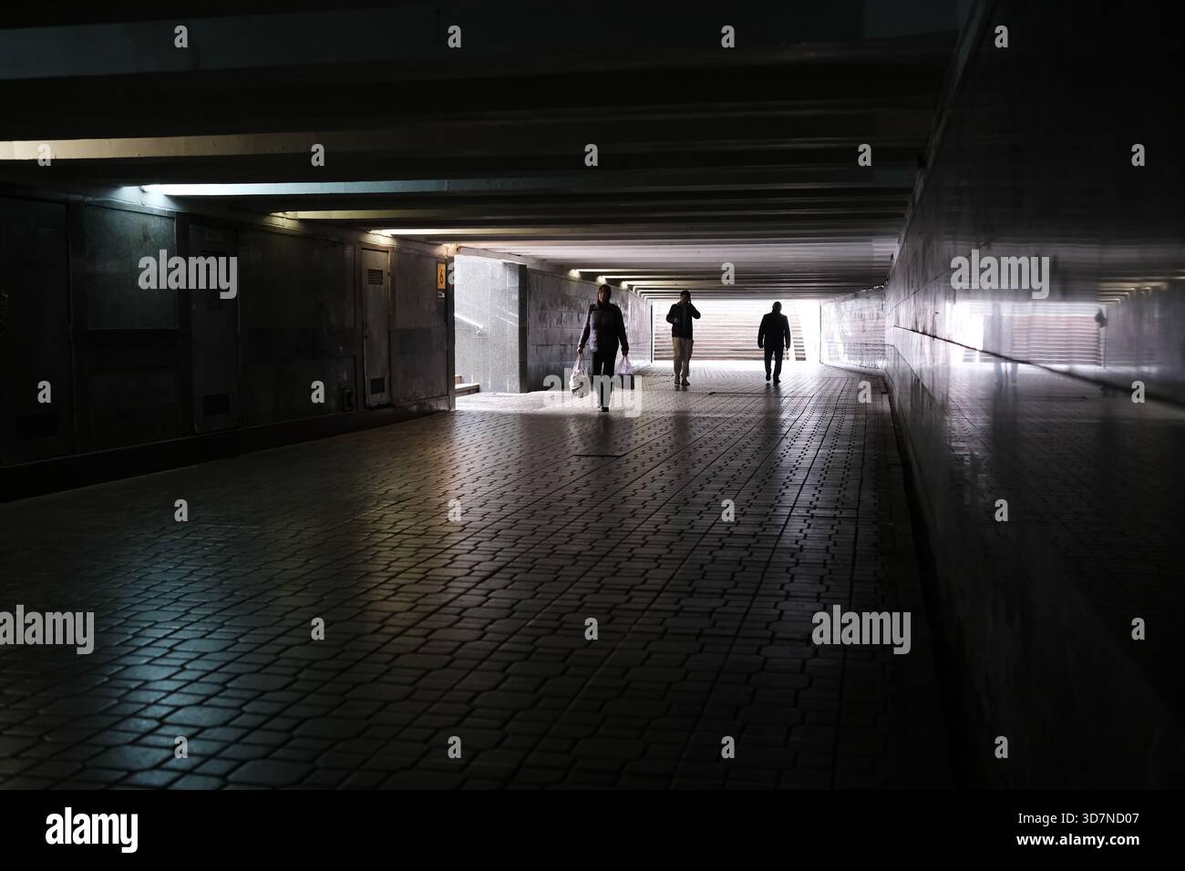 Le persone passeggiano attraverso un tunnel urbano poco illuminato, creando un senso di esplorazione. Foto Stock