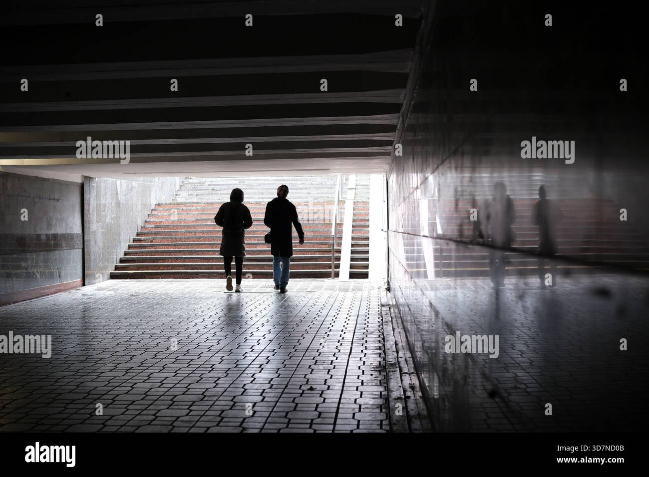 Le figure sagomate passeggiano attraverso un passaggio sotterraneo vicino ai gradini. Foto Stock