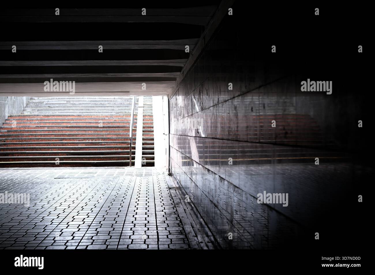 Il tunnel, poco illuminato, si apre sulle scale, gettando ombre e invitanti esplorazioni. Foto Stock