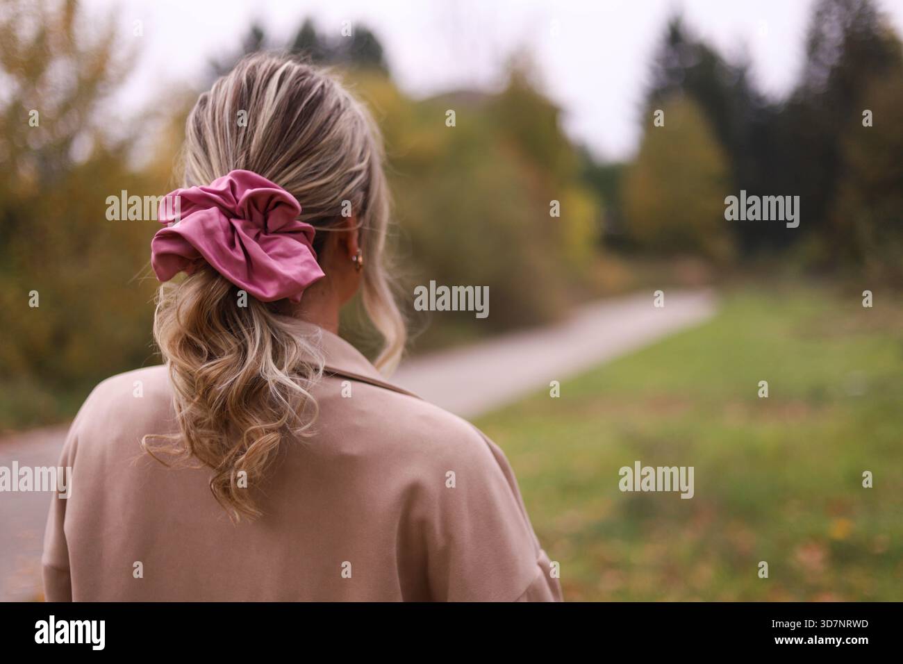 Donna con Scrunchie che cammina nella natura, ideale per temi di natura, moda e stile di vita. Foto Stock