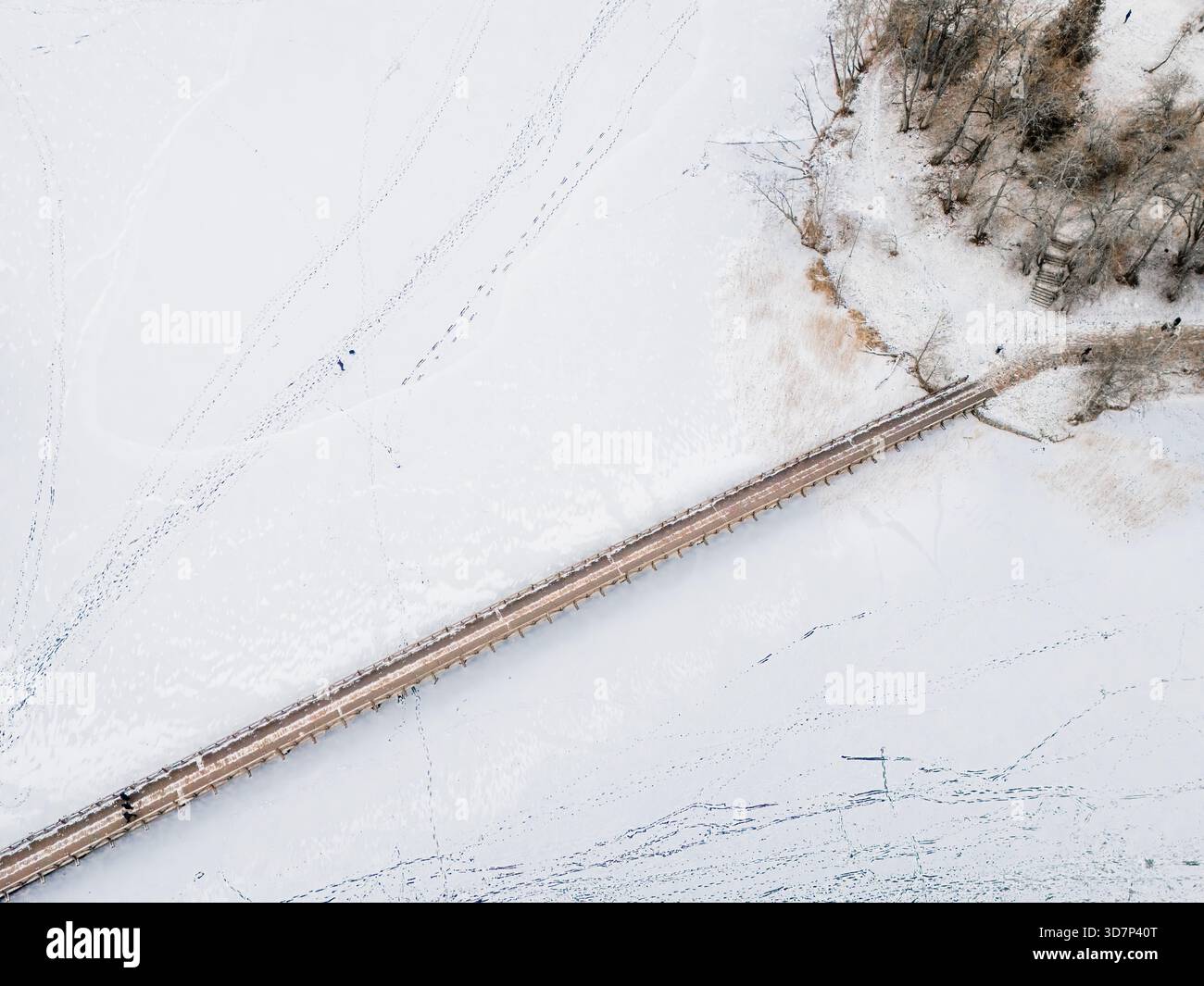 Vista aerea di un ponte di legno che attraversa la distesa ghiacciata, collegando la terra a una piccola isola sotto una coperta di neve, Trakai, Trakai, Lituania Foto Stock