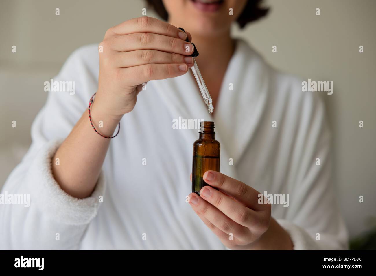 Flacone contagocce in vetro ambrato appoggiato sull'accappatoio mentre si pipetta il siero nel centro benessere Foto Stock