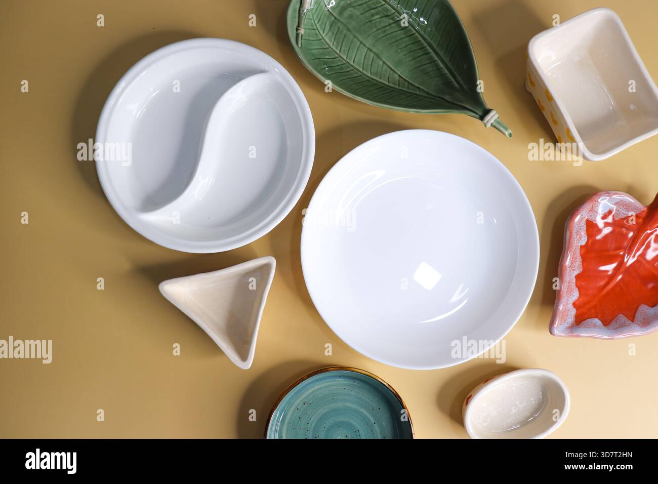 Composizione con piatti e ciotole in ceramica puliti e colorati su sfondo giallo Foto Stock