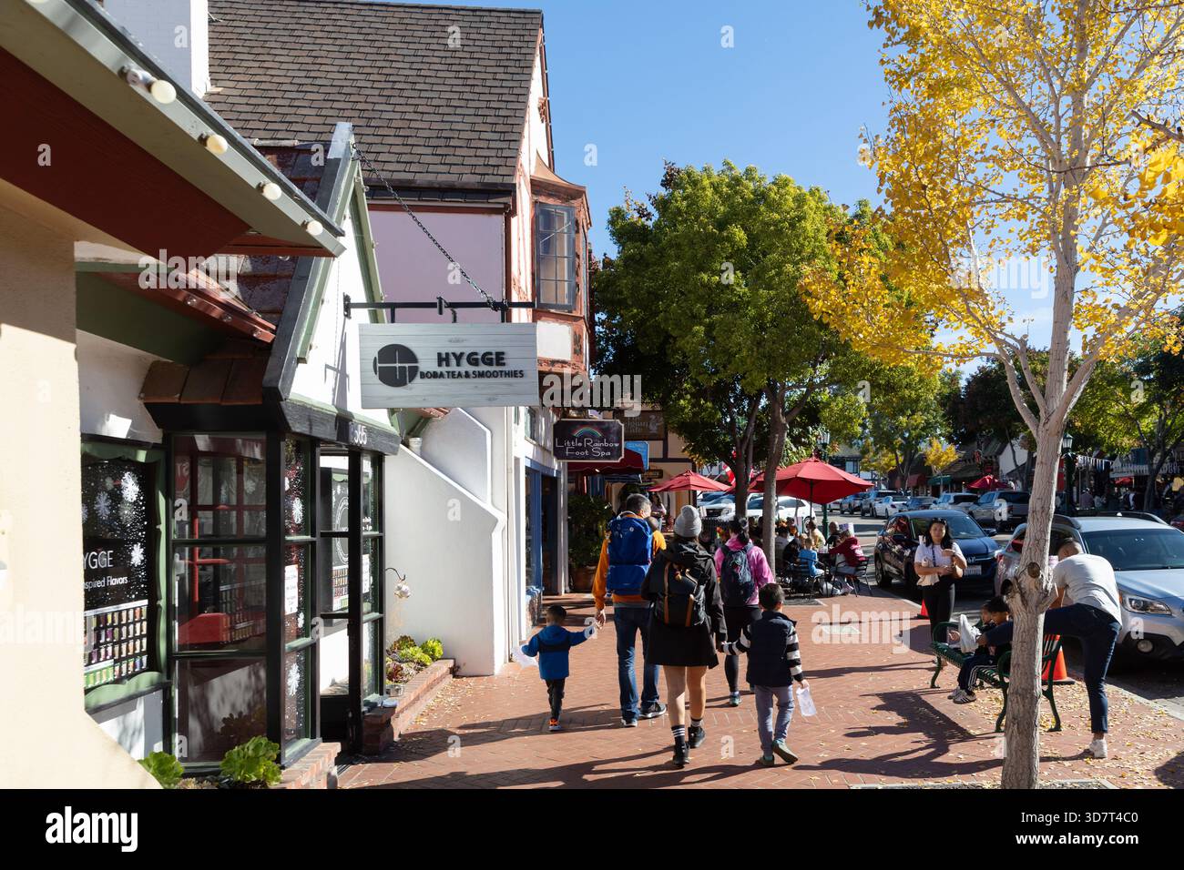 Persone che camminano lungo la strada autunnale vicino a negozi e caffetterie a Solvang, California Foto Stock