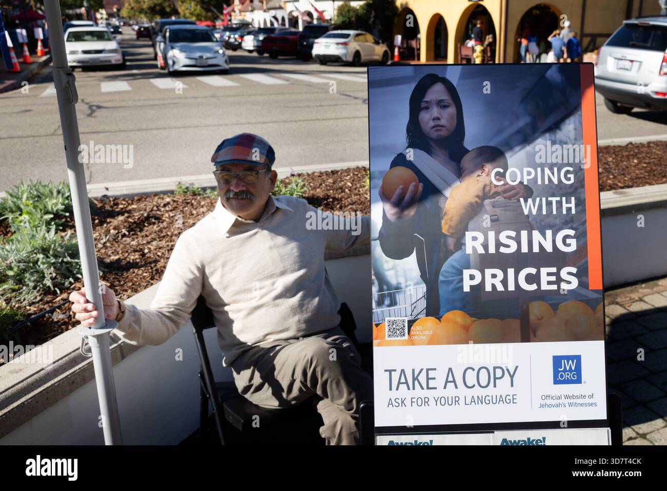 L'uomo seduto accanto alla letteratura religiosa sta con l'insegna dell'aumento dei prezzi Foto Stock