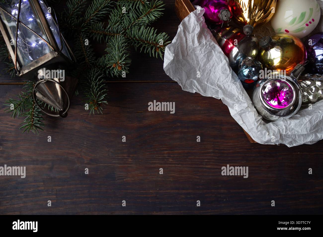 Composizione natalizia con ornamenti in vetro vintage, rami di pino, lanterna e fiocco di neve all'uncinetto fatto a mano su sfondo di legno scuro. Foto Stock