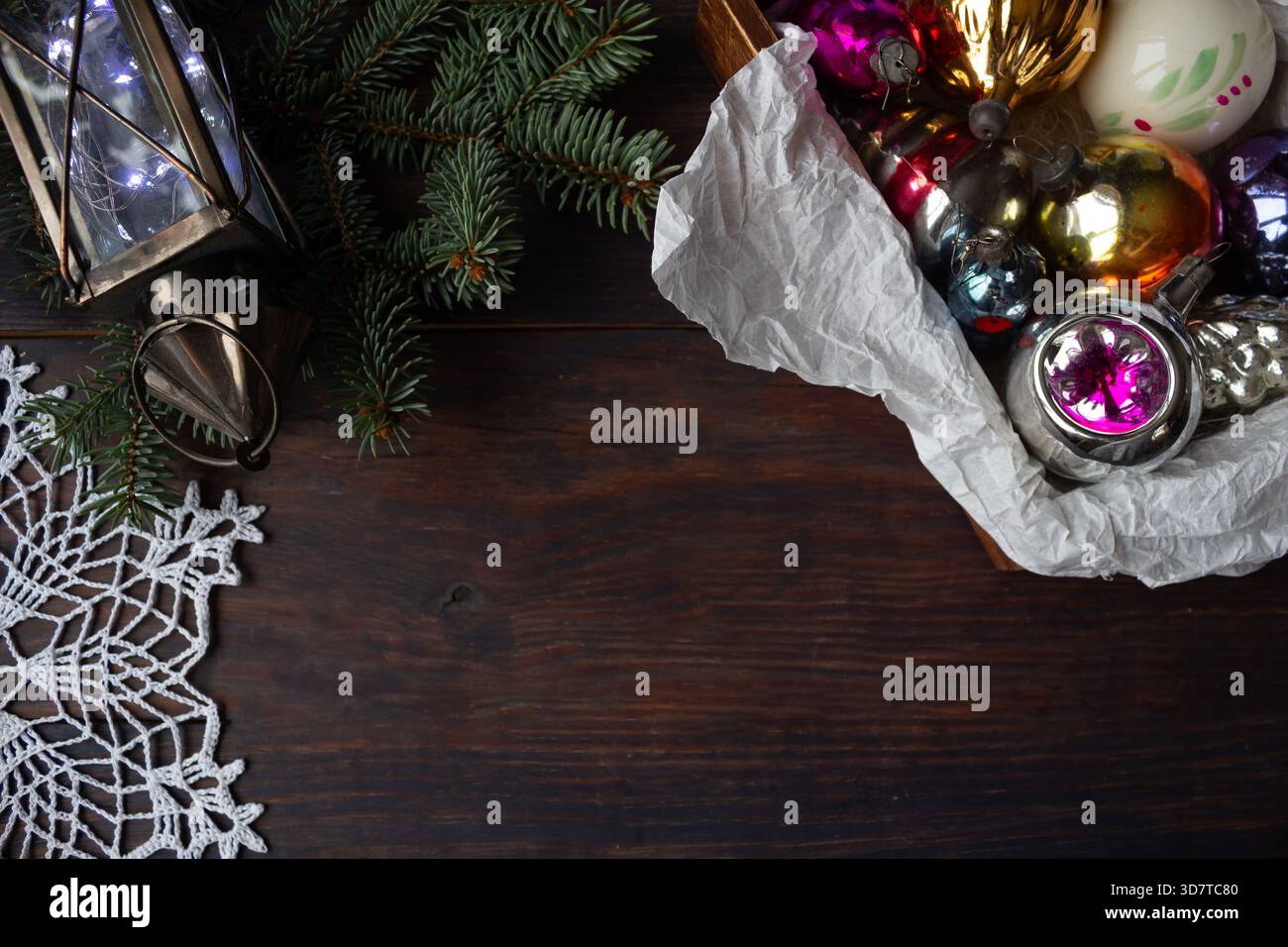 Composizione natalizia con ornamenti in vetro vintage, rami di pino, lanterna e fiocco di neve all'uncinetto fatto a mano su sfondo di legno scuro. Foto Stock
