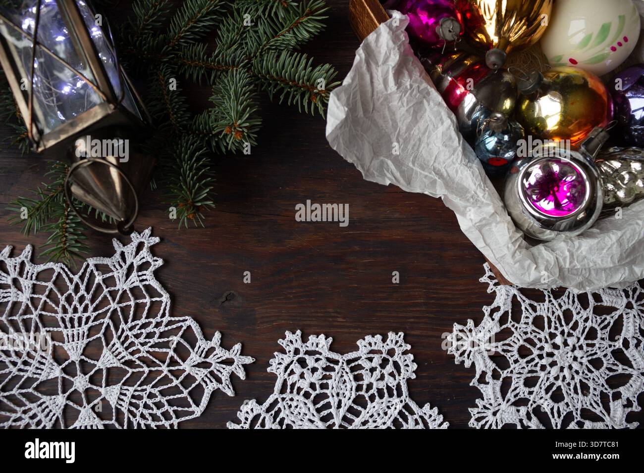 Composizione natalizia con ornamenti in vetro vintage, rami di pino, lanterna e fiocco di neve all'uncinetto fatto a mano su sfondo di legno scuro. Foto Stock