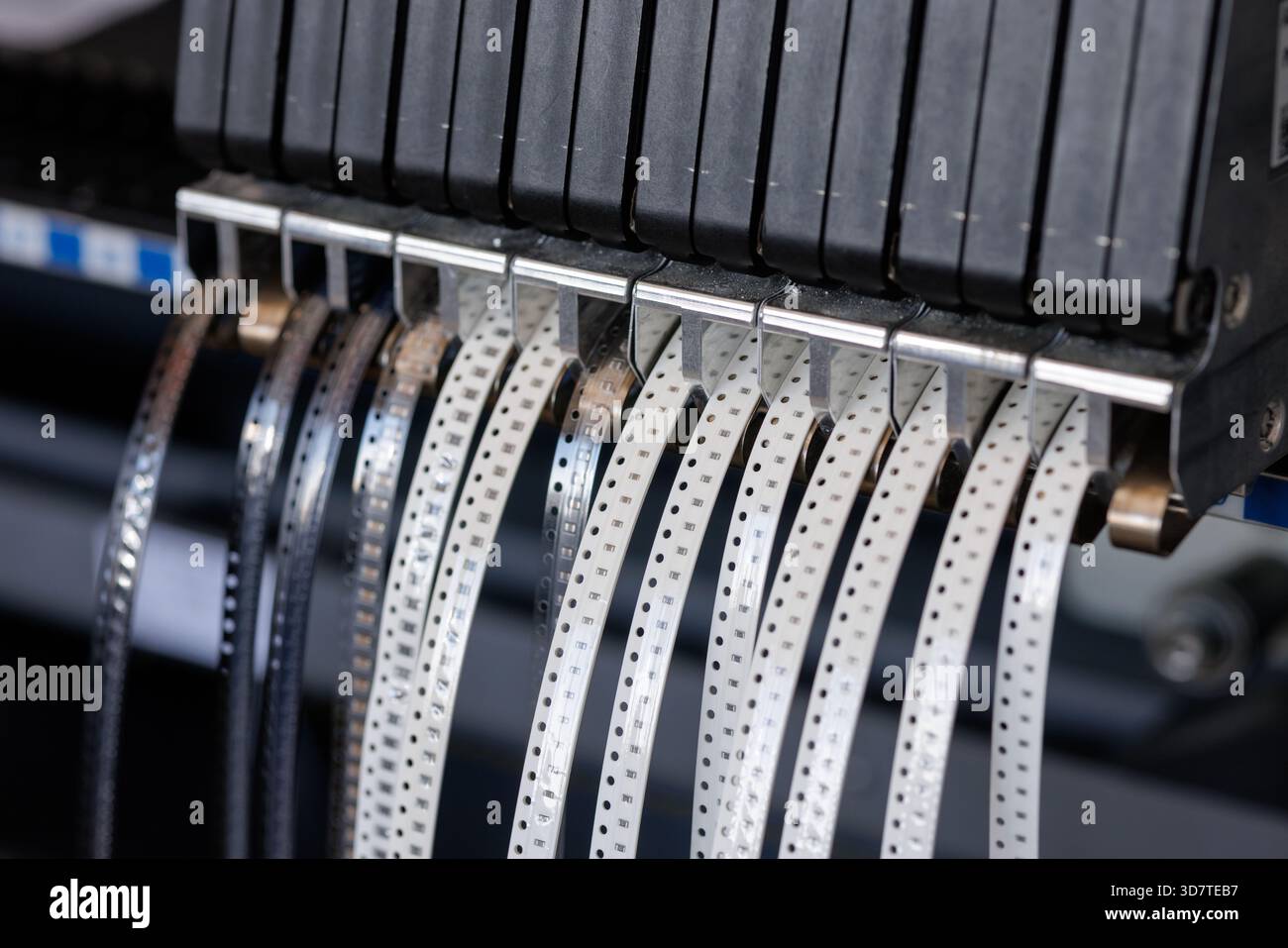 Primo piano dell'alimentatore di componenti SMT con bobine di parti microelettroniche utilizzate per l'assemblaggio automatizzato di PCB in impianti di produzione high-tech Foto Stock