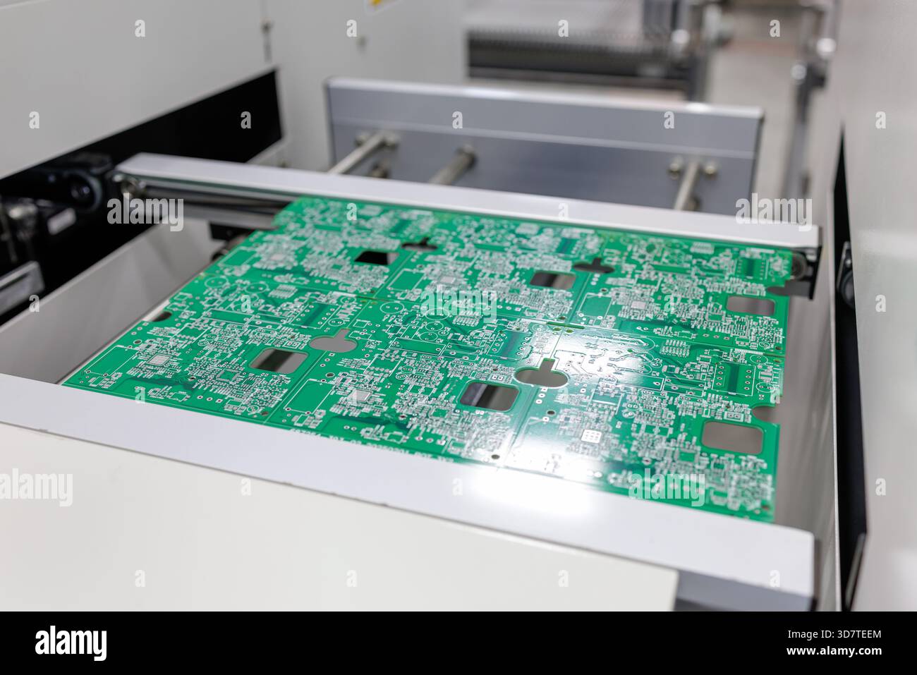 Pannello verde del circuito stampato che si sposta sul trasportatore all'interno della moderna macchina di produzione elettronica nell'officina di fabbrica Foto Stock