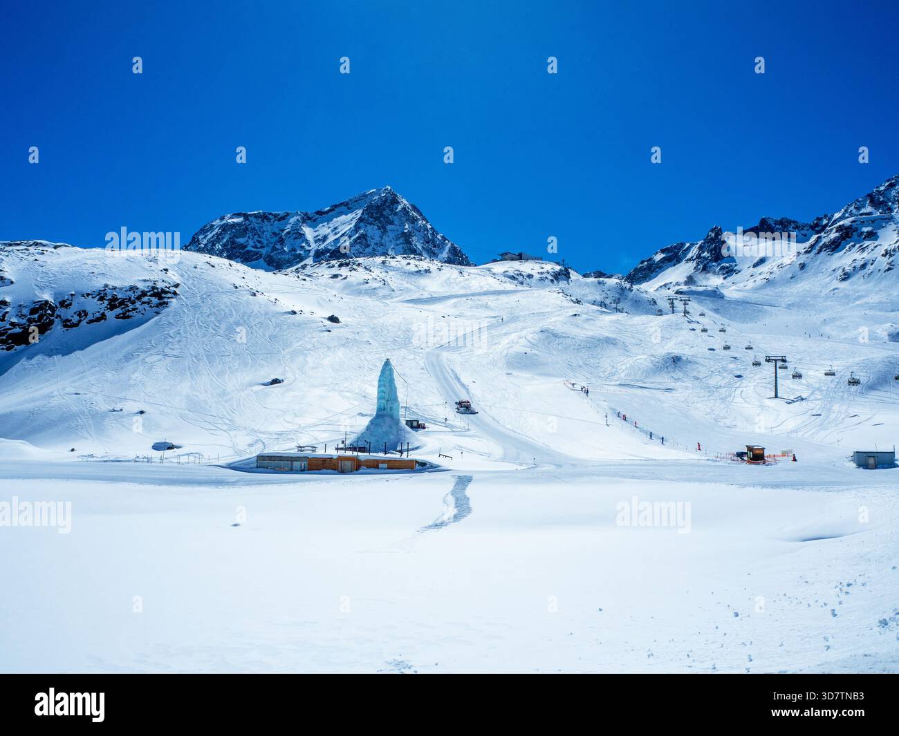 Ghiacciaio dello Stubai con piste da sci, seggiovie, traino, sciatori, torre di ghiaccio artificiale e snowgroom. Montagne rocciose, cielo blu e due spazi fotocopie Foto Stock