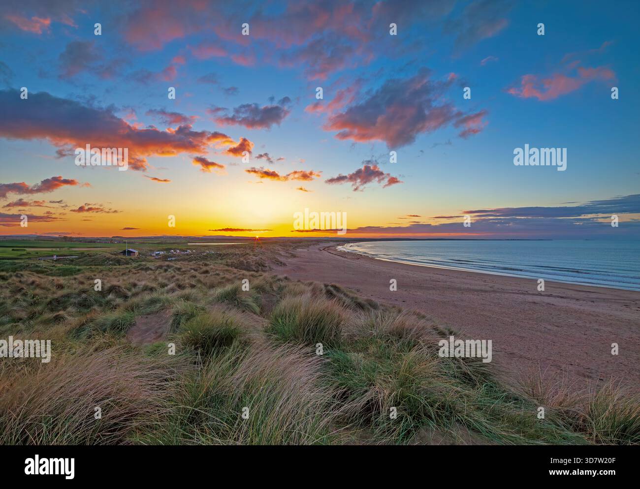 Un tramonto estivo sulla Druridge Bay nel Northumberland guardando verso Amble con un incantevole cielo colorato al tramonto Foto Stock