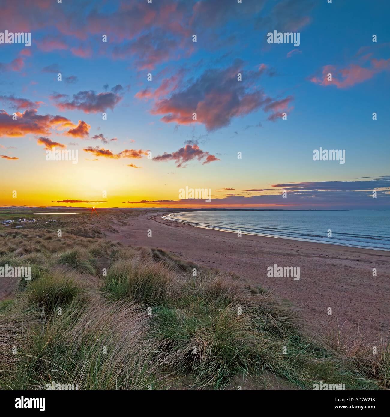 Un tramonto estivo sulla Druridge Bay nel Northumberland guardando verso Amble con un incantevole cielo colorato al tramonto Foto Stock