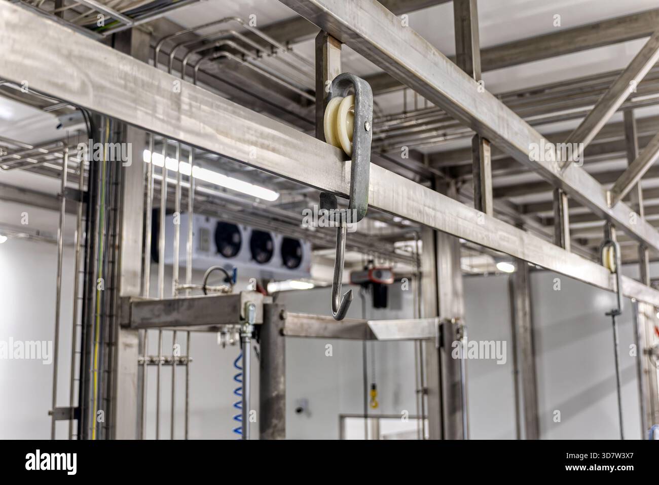 sistema di trasporto sospeso in acciaio inox con gancio e puleggia, utilizzato in impianti di lavorazione degli alimenti come impianti di confezionamento della carne Foto Stock