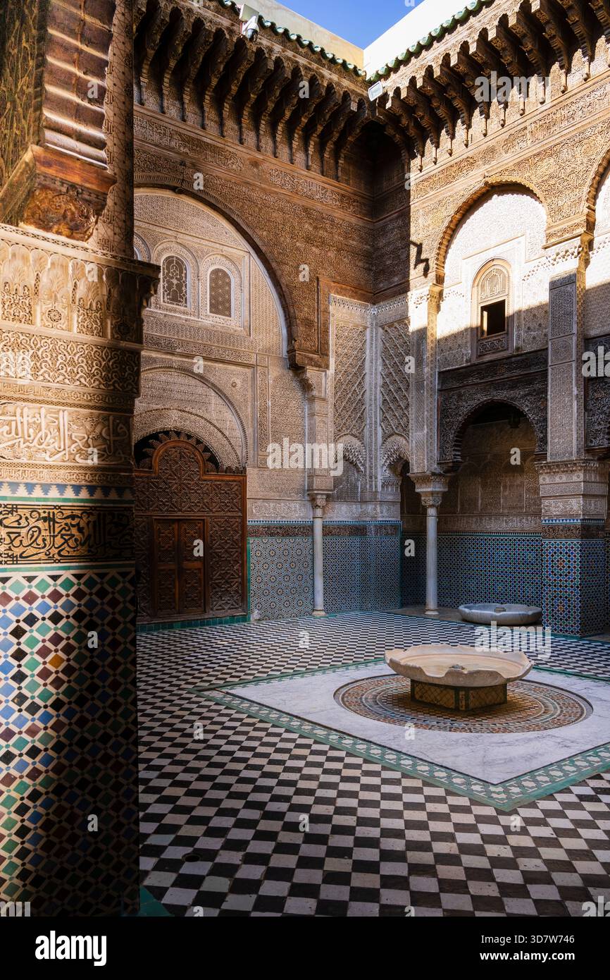 Cortile interno decorato con archi riccamente decorati e pavimento piastrellato, inondato dalla luce del sole. Fez, Fez-Meknes, Marocco settentrionale Foto Stock