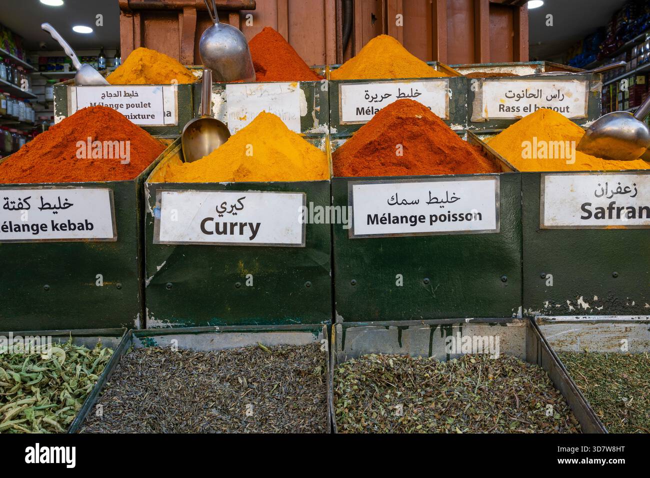 Varie spezie colorate in contenitori etichettati presso un mercato delle spezie. Marrakech, Marocco Foto Stock