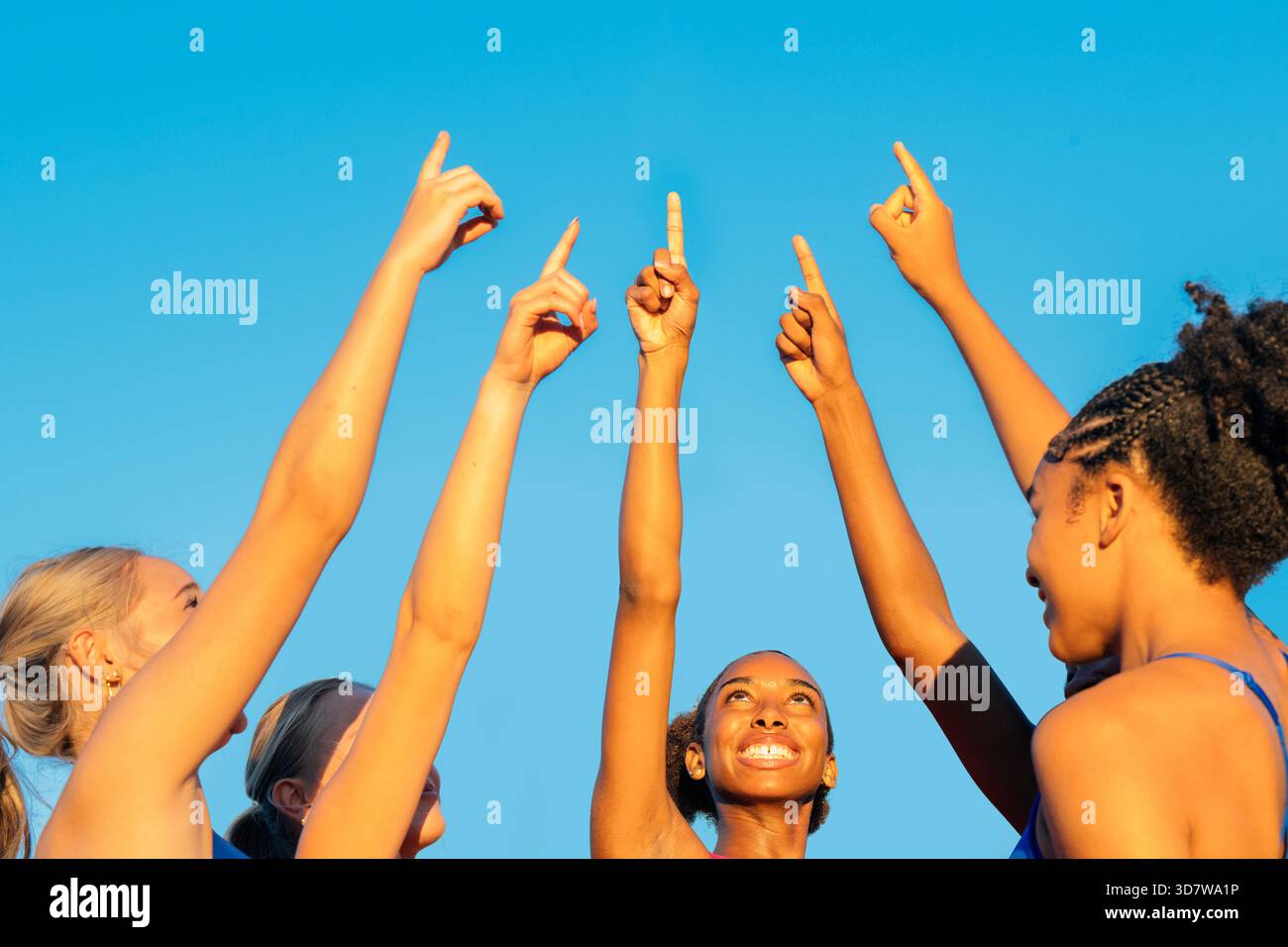 Gruppo eterogeneo che punta verso l'alto sotto un cielo blu brillante, gioioso e unito. WASHINGTON, STATI UNITI Foto Stock