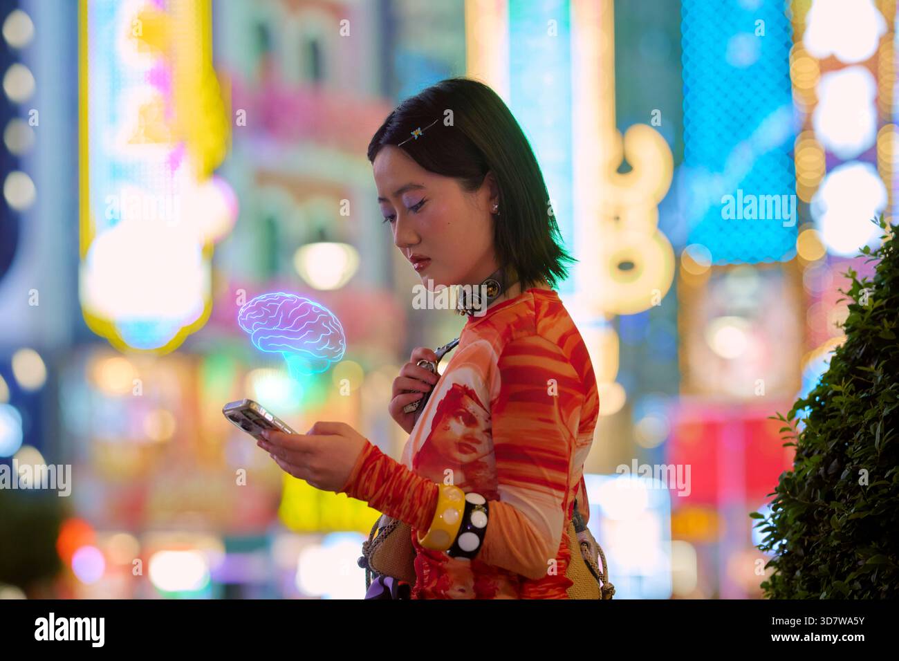 Un giovane adulto che utilizza un nuovo smartphone ai con vivaci luci della città sullo sfondo. Shanghai, Cina Foto Stock