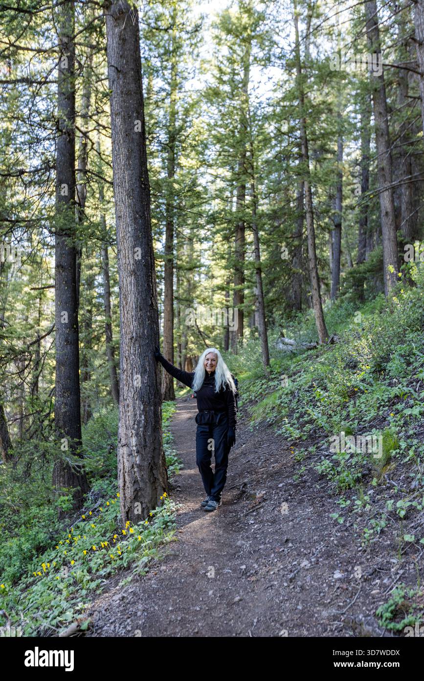 Ritratto di donna sorridente in piedi su un sentiero nella foresta Foto Stock