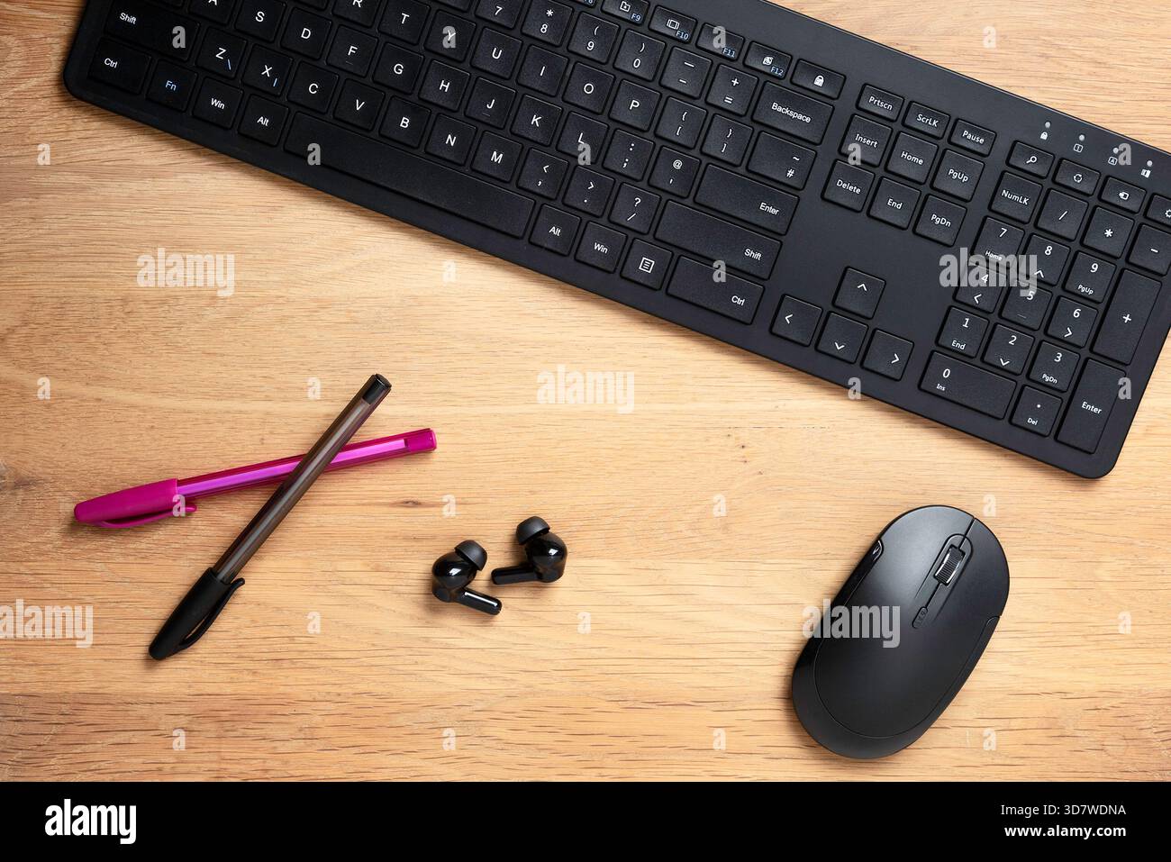 Scrivania con tastiera, mouse, penne e auricolari Foto Stock