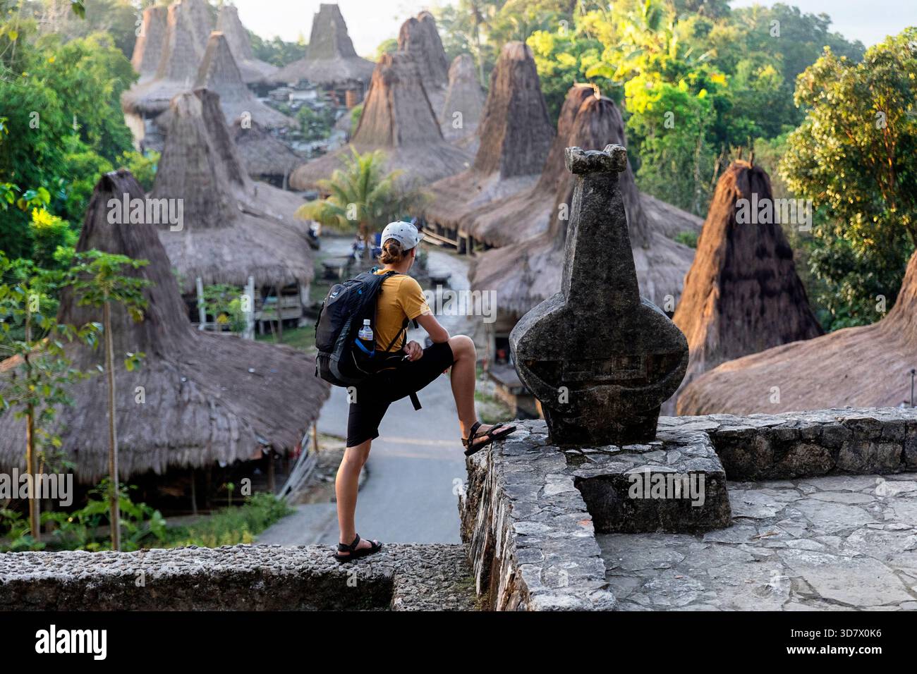 Un turista durante un viaggio turistico nel villaggio idilliaco di Praijing sull'isola di Sumba, che esplora case tradizionali uniche con tetti alti. Foto Stock
