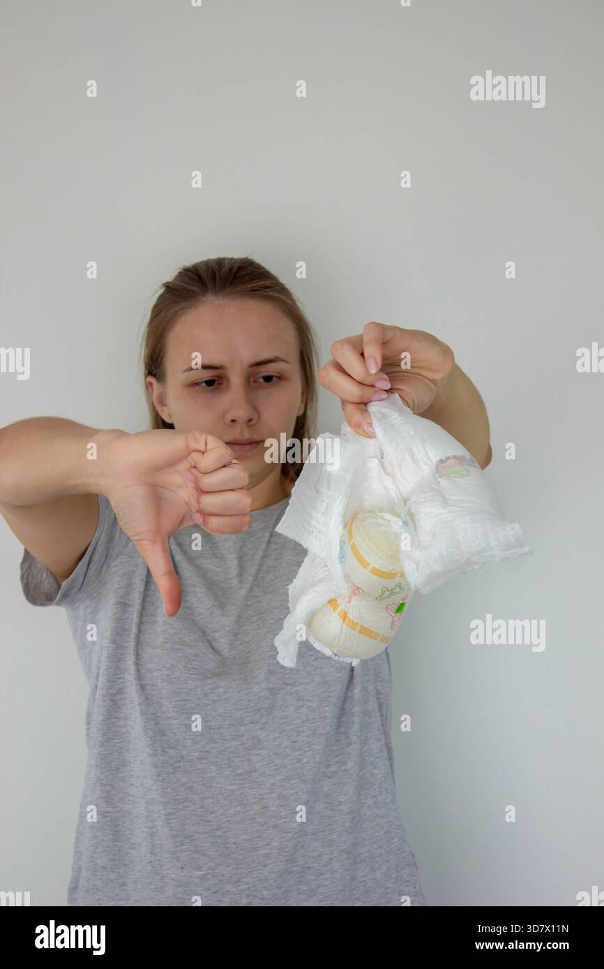 La donna mostra il pollice verso il basso che non piace ai pannolini usa e getta, esprimendo insoddisfazione. Foto Stock