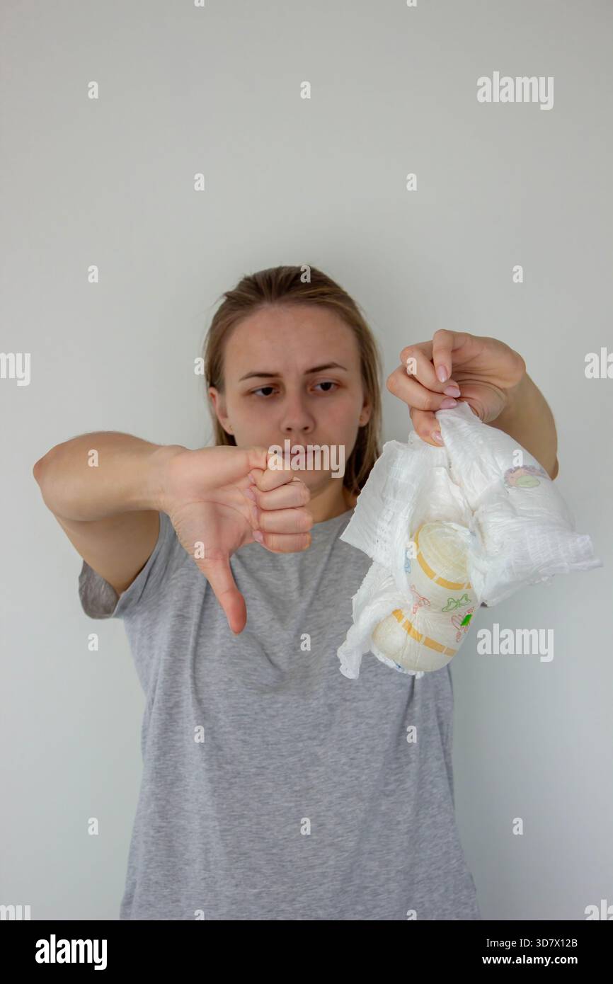 La donna mostra il pollice verso il basso che non piace ai pannolini usa e getta, esprimendo insoddisfazione. Foto Stock