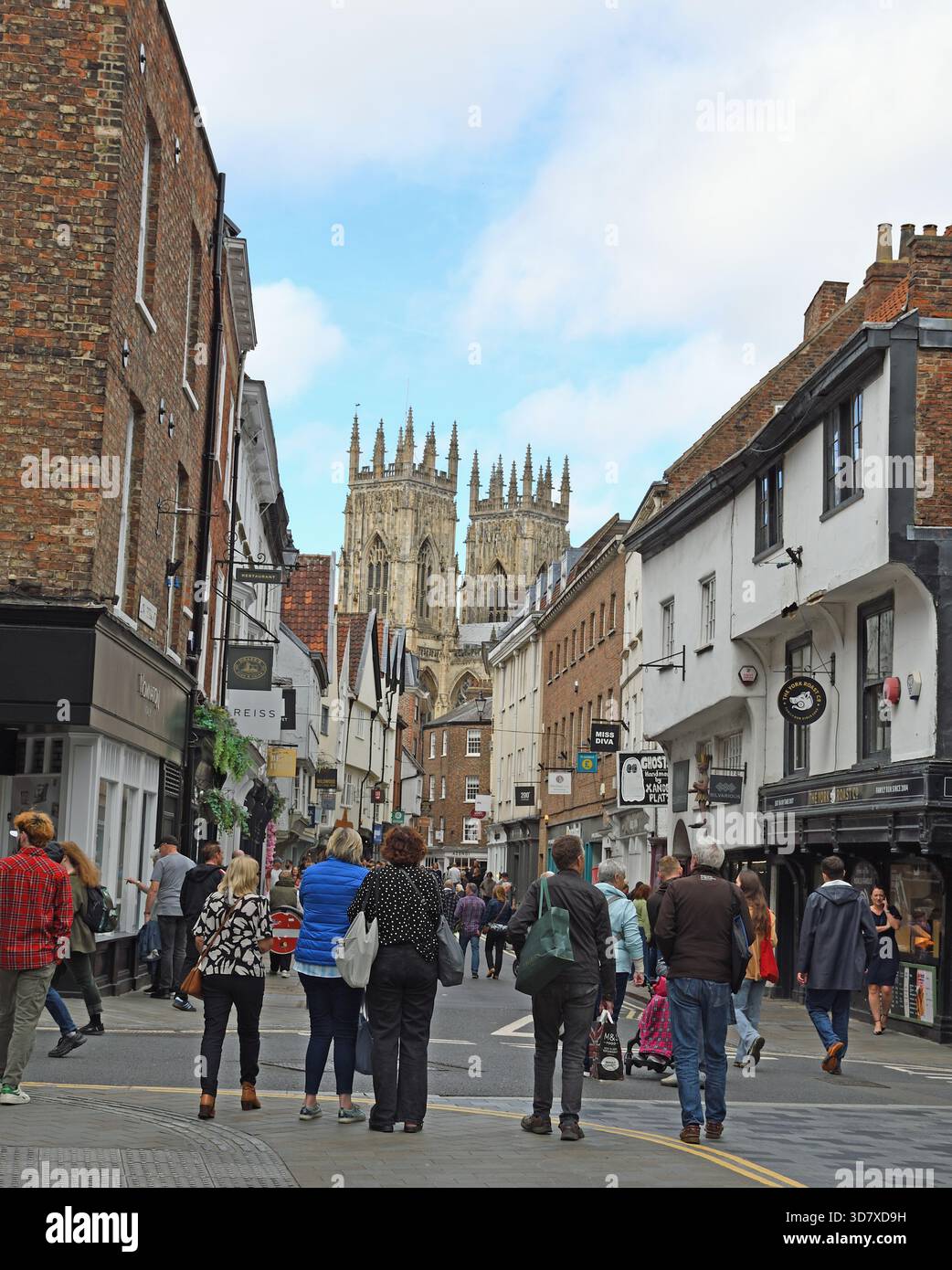 Persone che camminano lungo Low Petergate, Pedestrian Street, York, Yorkshire, Inghilterra, Regno Unito. Due torri della York Minster. Foto Stock