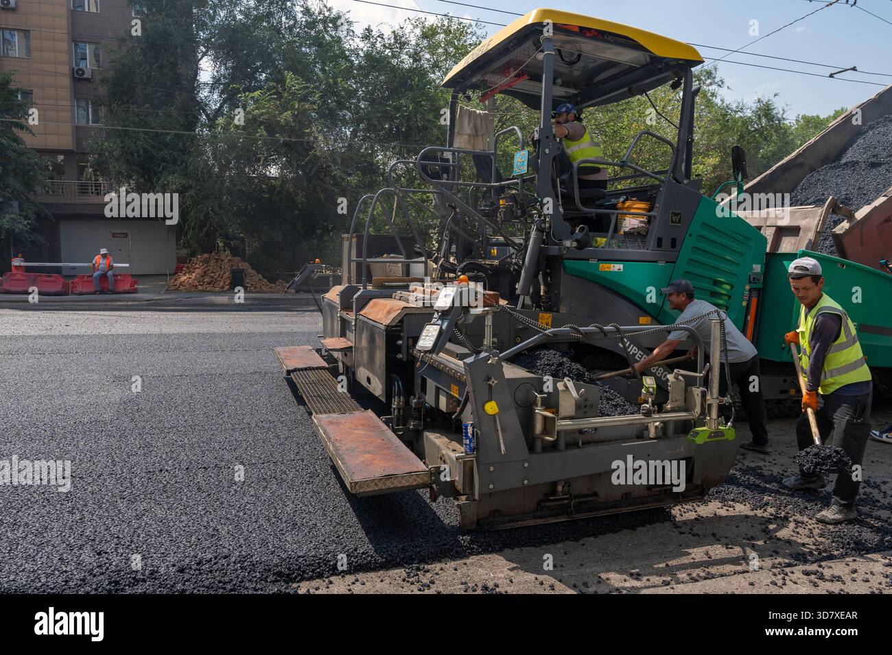 Almaty, Kazakistan - 17 luglio 2025: I lavoratori gestiscono un'asfaltatrice lungo la strada. Attrezzature specializzate Foto Stock