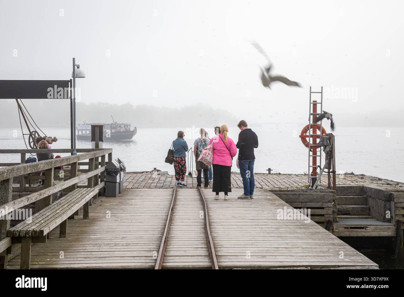 Persone in attesa del traghetto sul molo dei traghetti di Lonna Island in una nebbia giornata a Helsinki, Finlandia Foto Stock