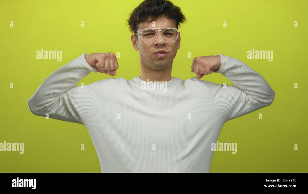 L'uomo flette i pugni in studio, mostrando tono ed energia muscolari con una postura determinata e sicurezza. Foto Stock
