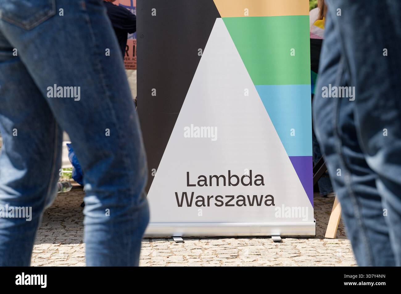 Primo piano di uno striscione Lambda Warszawa parzialmente oscurato dalle persone che passano accanto. Foto Stock